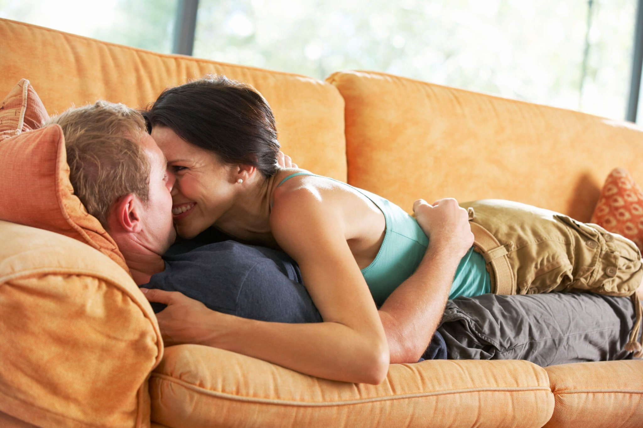 Влюбленные романтично занимаются любовью на красном диване 